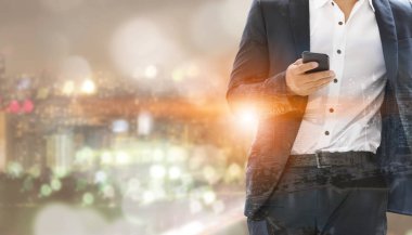Genç işadamı cep telefonunuzun ve modern şehir binaları arka plan ile. Gelecekteki telekomünikasyon teknolojisi ve internet şeyler (çok) kavramının.