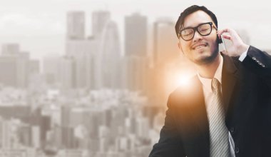 Genç işadamı istimal hareket eden telefon ile modern şehir binaları arka plan.