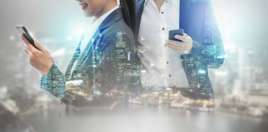 Cep telefonu ile modern şehir binaları arka plan kullanarak genç iş adamları. Gelecekteki telekomünikasyon teknolojisi ve internet şeyler (çok) kavramının.