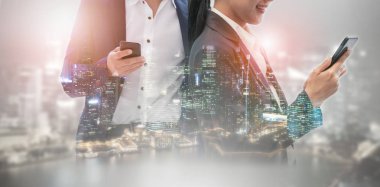 Cep telefonu ile modern şehir binaları arka plan kullanarak genç iş adamları. Gelecekteki telekomünikasyon teknolojisi ve internet şeyler (çok) kavramının.