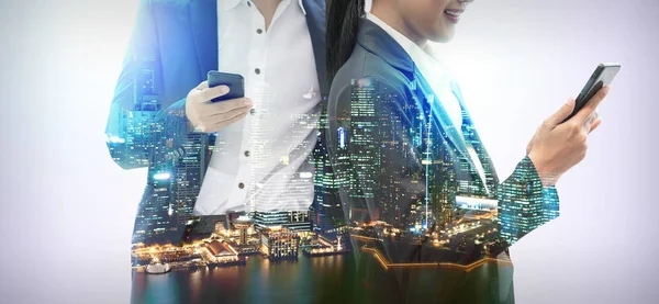 Cep telefonu ile modern şehir binaları arka plan kullanarak genç iş adamları. Gelecekteki telekomünikasyon teknolojisi ve internet şeyler (çok) kavramının.