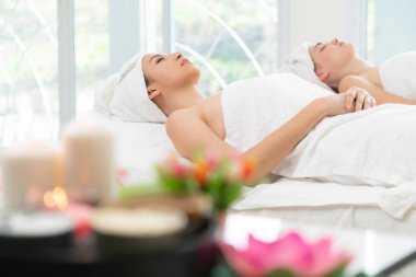 Spa yatağında uzanan rahat genç bir kadın lüks bir spa merkezinde yüz bakımı ve masaj için hazırlandı. Sağlık, stres atma ve gençleştirme kavramı.