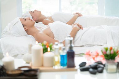 Spa yatağında uzanan rahat genç bir kadın lüks bir spa merkezinde yüz bakımı ve masaj için hazırlandı. Sağlık, stres atma ve gençleştirme kavramı.