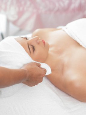 Spa yatağında uzanan rahat genç bir kadın lüks bir spa merkezinde yüz bakımı ve masaj için hazırlandı. Sağlık, stres atma ve gençleştirme kavramı.