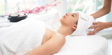 Spa yatağında uzanan rahat genç bir kadın lüks bir spa merkezinde yüz bakımı ve masaj için hazırlandı. Sağlık, stres atma ve gençleştirme kavramı.