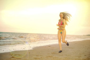 Çekici kadın runner yaz aylarında tropikal Kum Plajı üzerinde çalışır. Sağlıklı yaşam tarzı ve koşma spor kavramı.