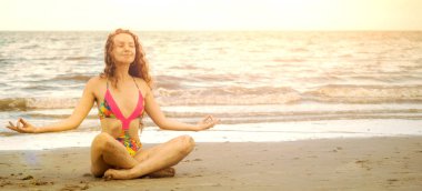 Genç kadın pratik yoga poz sahilde yaz. Sağlıklı yaşam tarzı ve meditasyon.