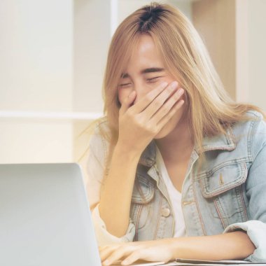 Genç kadın ofiste bilgisayar kullanırken güler. Küçük işletme kavramı.