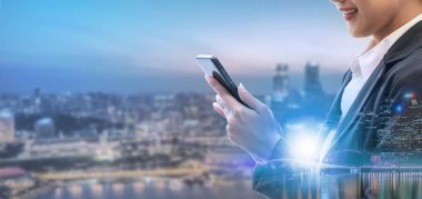 Cep telefonu ile modern şehir binaları arka plan kullanarak genç iş kadını. Gelecekteki telekomünikasyon teknolojisi ve internet şeyler (çok) kavramının.