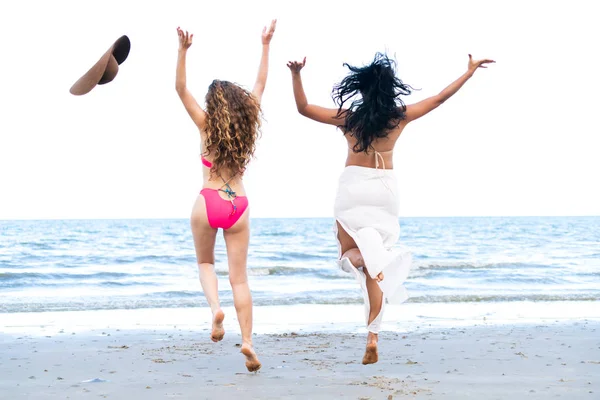 Mutlu kadın birlikte havada yaz tatil tropikal Kum Plajı üzerinde atlama bikinis. Seyahat yaşam tarzı.