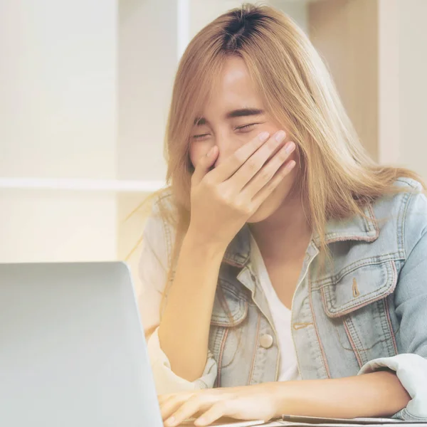 Genç kadın ofiste bilgisayar kullanırken güler. Küçük işletme kavramı.