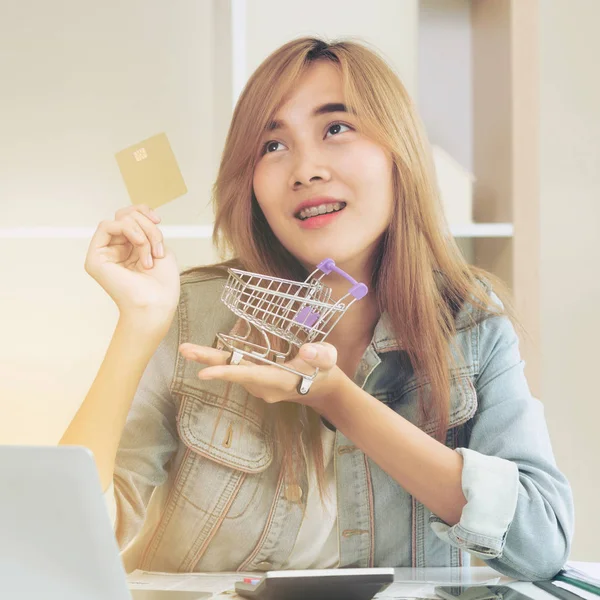 Kredi kartı evde tutan ve online mağazadan alışveriş hakkında düşünme güzel kadın. Modern online alışveriş kavramı.