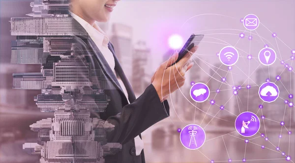 Cep telefonu ile modern şehir binaları arka plan kullanarak genç iş kadını. Gelecekteki telekomünikasyon teknolojisi ve internet şeyler (çok) kavramının.