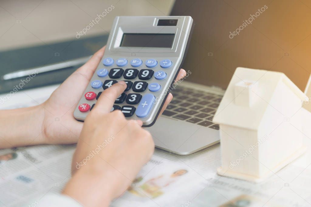 Woman accountant or bank worker uses calculator in the office to calculate house loan credit bureaucracy.