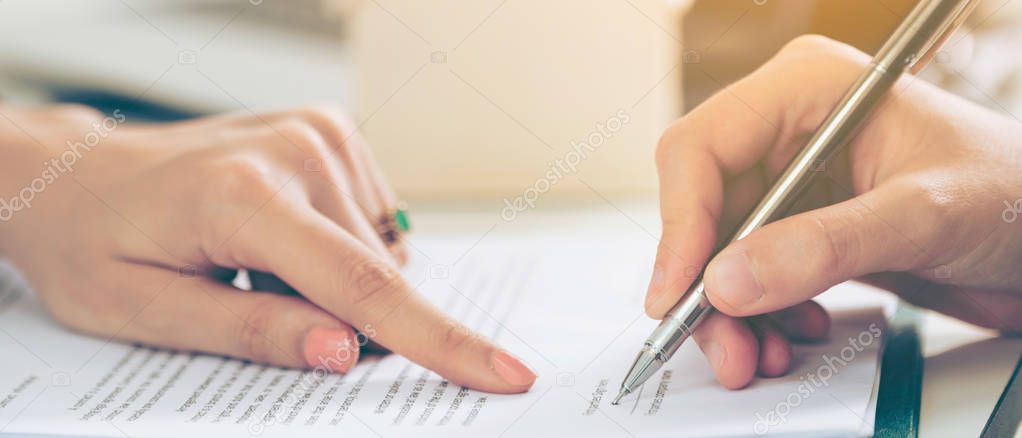 Businesswoman signs agreement contract with another businesswoman at the office. Close up shot at the woman's hand. Concept of business partnership and legal activities of lawyer.