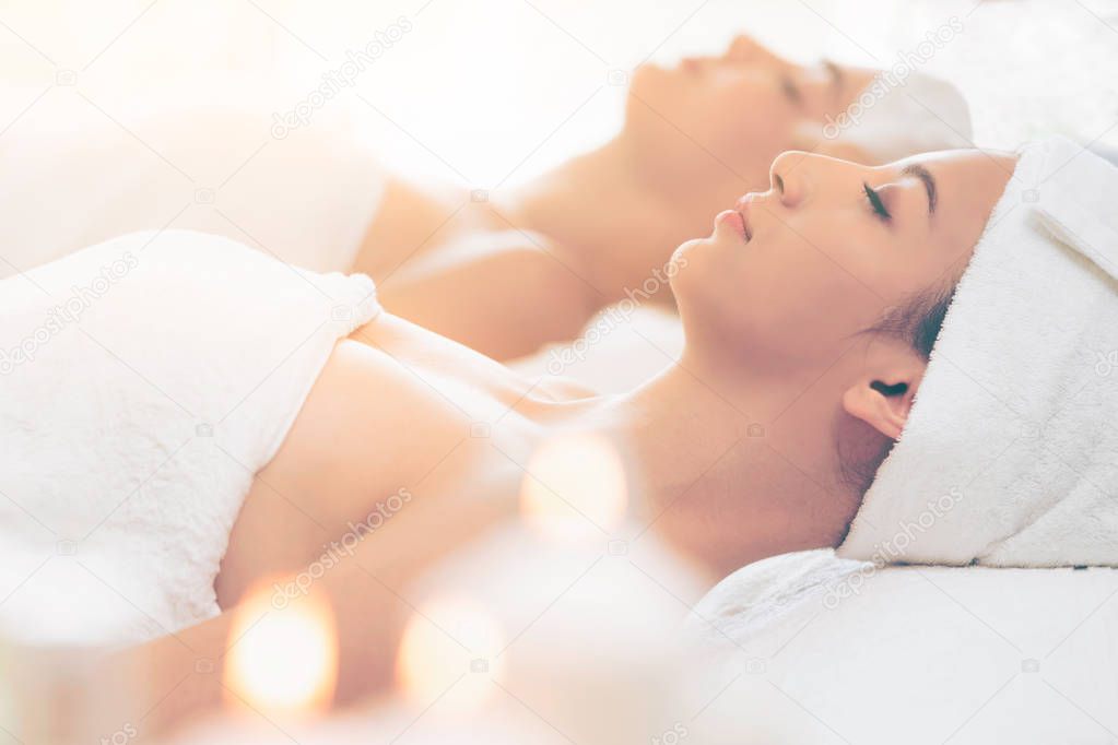 Relaxed young woman lying on spa bed prepared for facial treatment and massage in luxury spa resort. Wellness, stress relief and rejuvenation concept.