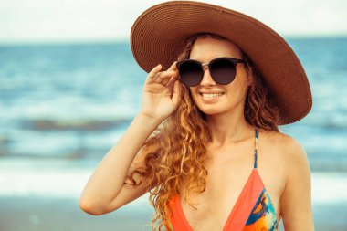Tatil seyahat etmek tatil için yaz aylarında tropikal plaj keyfi yerinde mayo giyen mutlu genç kadın.