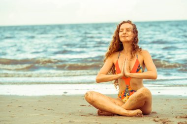 Genç kadın pratik yoga poz sahilde yaz. Sağlıklı yaşam tarzı ve meditasyon.