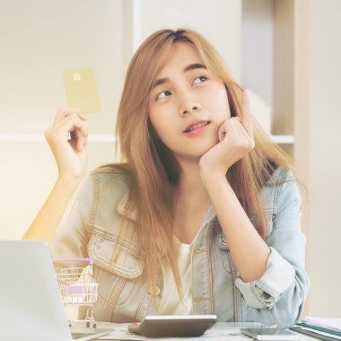 Kredi kartı evde tutan ve online mağazadan alışveriş hakkında düşünme güzel kadın. Modern online alışveriş kavramı.