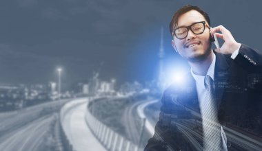 Genç işadamı istimal hareket eden telefon ile modern şehir binaları arka plan.