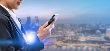 Cep telefonu ile modern şehir binaları arka plan kullanarak genç iş kadını. Gelecekteki telekomünikasyon teknolojisi ve internet şeyler (çok) kavramının.