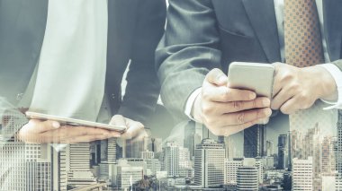 Cep telefonu ile modern şehir binaları arka plan kullanarak genç iş adamları. Gelecekteki telekomünikasyon teknolojisi ve internet şeyler (çok) kavramının.