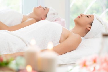 Spa yatağında uzanan rahat genç bir kadın lüks bir spa merkezinde yüz bakımı ve masaj için hazırlandı. Sağlık, stres atma ve gençleştirme kavramı.