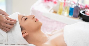 Spa yatağında uzanan rahat genç bir kadın lüks bir spa merkezinde yüz bakımı ve masaj için hazırlandı. Sağlık, stres atma ve gençleştirme kavramı.