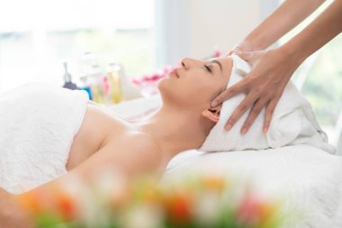 Spa yatağında uzanan rahat genç bir kadın lüks bir spa merkezinde yüz bakımı ve masaj için hazırlandı. Sağlık, stres atma ve gençleştirme kavramı.