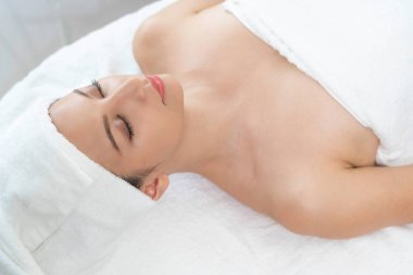 Spa yatağında uzanan rahat genç bir kadın lüks bir spa merkezinde yüz bakımı ve masaj için hazırlandı. Sağlık, stres atma ve gençleştirme kavramı.