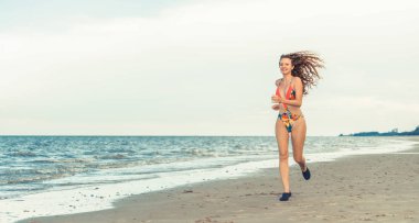 Çekici kadın runner yaz aylarında tropikal Kum Plajı üzerinde çalışır. Sağlıklı yaşam tarzı ve koşma spor kavramı.