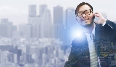 Genç işadamı istimal hareket eden telefon ile modern şehir binaları arka plan.