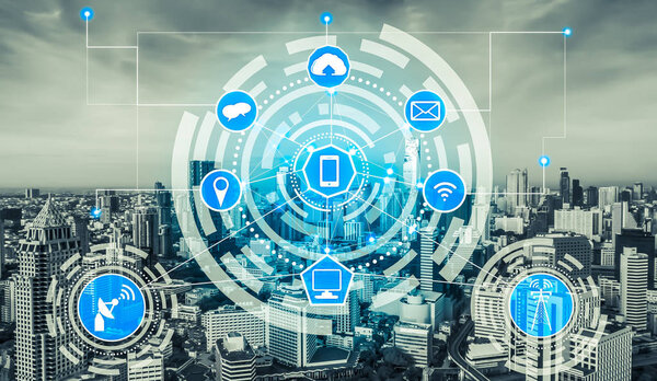 Smart city wireless communication network with graphic showing concept of internet of things (IOT) and information communication technology (ICT) against modern city buildings in the background.