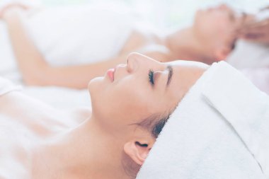 Spa yatağında uzanan rahat genç bir kadın lüks bir spa merkezinde yüz bakımı ve masaj için hazırlandı. Sağlık, stres atma ve gençleştirme kavramı.