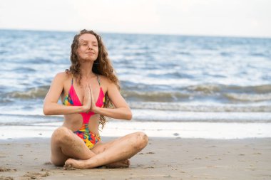 Genç kadın pratik yoga poz sahilde yaz. Sağlıklı yaşam tarzı ve meditasyon.