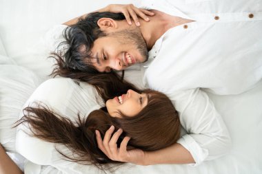 Mutlu genç çift rahatlatıcı sabah uyandıktan sonra eve yatak odasında.