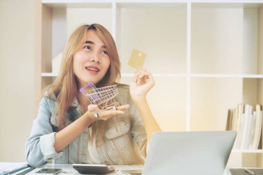 Kredi kartı evde tutan ve online mağazadan alışveriş hakkında düşünme güzel kadın. Modern online alışveriş kavramı.