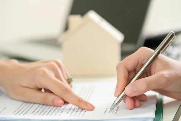 Client signs document regarding real estate activity. Lawyer or real estate agent points at the signature point. Business concept of selling and buying house.