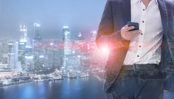 Young businessman using mobile phone with modern city buildings background. Future telecommunication technology and internet of things ( IOT ) concept.