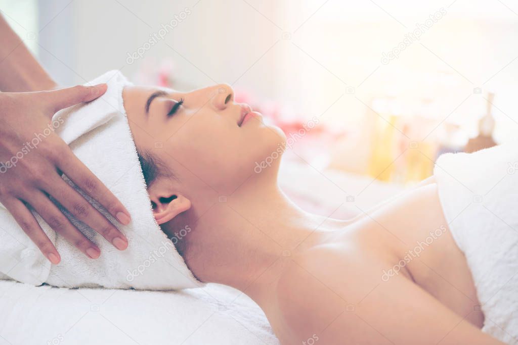 Relaxed young woman lying on spa bed prepared for facial treatment and massage in luxury spa resort. Wellness, stress relief and rejuvenation concept.