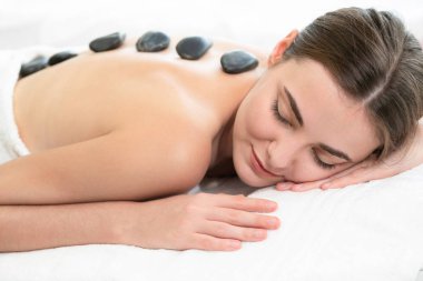 Kadın kaplıca salonunda profesyonel güzellik terapisti tarafından sıcak taş masajı görüyor. Lüks sağlık, sırt stresi ve gençleştirme kavramı..