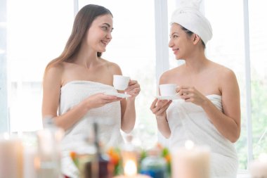 İki kadın lüks günlük kaplıcada konuşma yaparken çay veya bitkisel içecekler içme. Sağlık, eğlence ve sağlık kavramı.