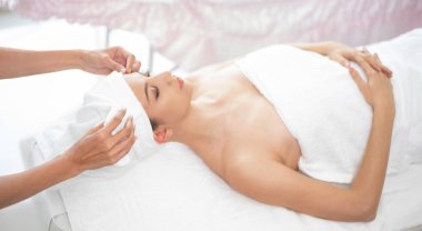 Spa yatağında uzanan rahat genç bir kadın lüks bir spa merkezinde yüz bakımı ve masaj için hazırlandı. Sağlık, stres atma ve gençleştirme kavramı.