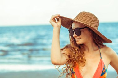 Tatil seyahat etmek tatil için yaz aylarında tropikal plaj keyfi yerinde mayo giyen mutlu genç kadın.