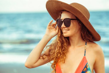 Tatil seyahat etmek tatil için yaz aylarında tropikal plaj keyfi yerinde mayo giyen mutlu genç kadın.