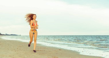 Çekici kadın runner yaz aylarında tropikal Kum Plajı üzerinde çalışır. Sağlıklı yaşam tarzı ve koşma spor kavramı.