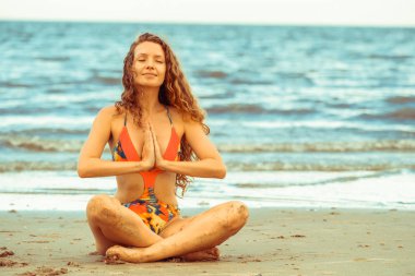 Genç kadın pratik yoga poz sahilde yaz. Sağlıklı yaşam tarzı ve meditasyon.