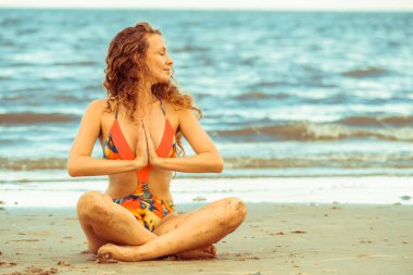 Genç kadın pratik yoga poz sahilde yaz. Sağlıklı yaşam tarzı ve meditasyon.