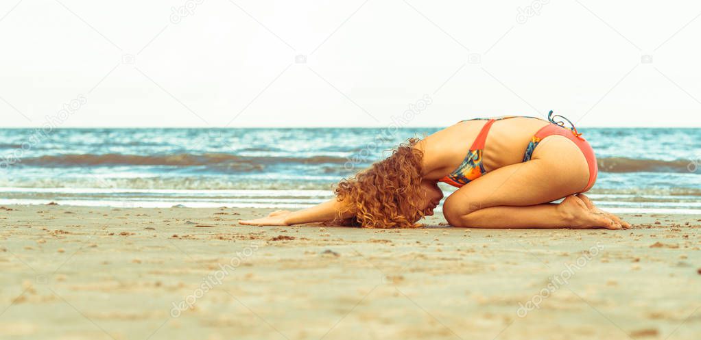 Young woman practicing yoga pose on the beach in summer. Healthy lifestyle and meditation.