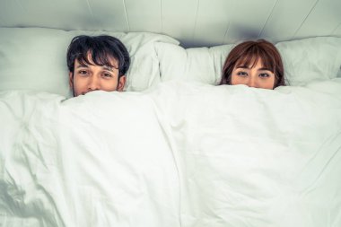 Mutlu genç çift rahatlatıcı sabah uyandıktan sonra eve yatak odasında.